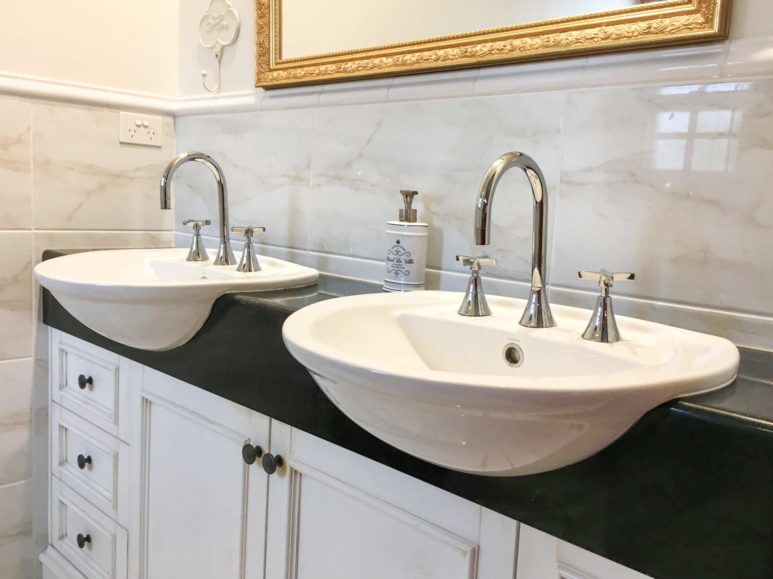 dual basins in a vanity ensuite with a gold mirror